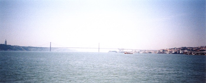 The suspension bridge spanning the River Tagus, connecting the north and south sides of Lisbon, with the giant Christ statue visible on the left