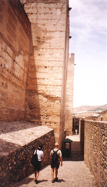 Eric and Susanne marching off beside the giant, leaning walls of the Alcazaba